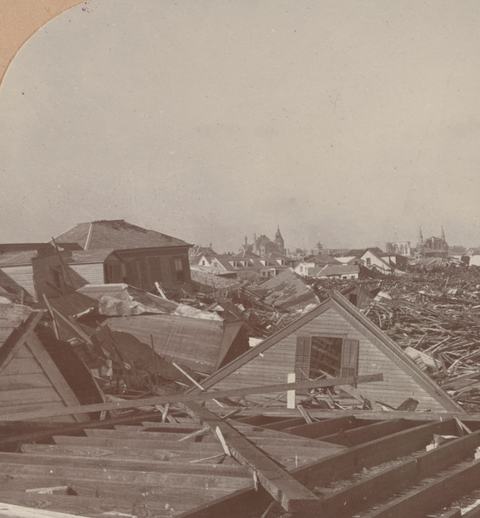 Sepia photograph of a field of wrecked houses and timber stretching to the horizon.